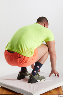 Joel  1 dressed green sneakers kneeling orange shorts sports…